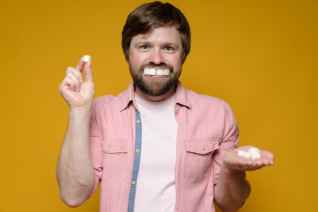 Funny man put sugar lumps in mouth as if it were teeth and smiles