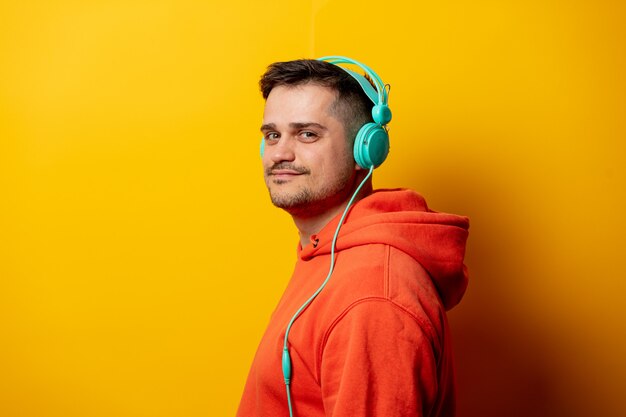 Funny man with headphones on yellow wall