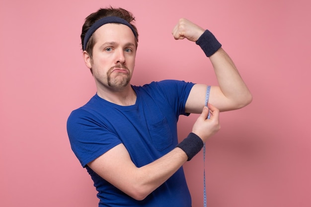 Funny man with mustache being proud of himself and measures biceps