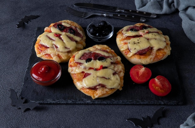 Funny mini pizzas mummies with sausage and cheese for Halloween party served with black olives