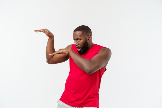 Funny and playful adult African American guy standing in profile in martial arts pose with raised palms, frowning and staring.