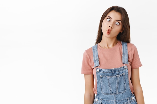 Funny playful cute girlfriend not scared showing her hilarious side playing charades mimicking fish folding lips and squinting shifting eyes standing white background upbeat grimacing