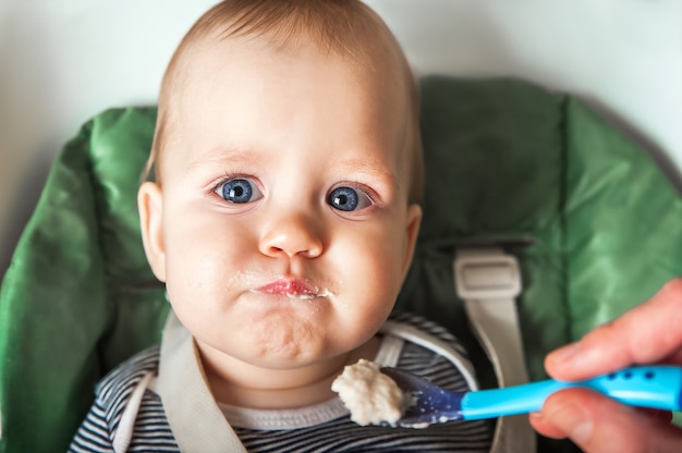 Funny portrait of toddler eating closeup Complementary feeding of child with porridge at 9 months Zucchini cauliflower broccoli