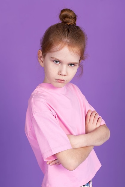 Funny positive girl in jeans and a Tshirt laughing grimacing looking at the camera isolated on a purple background Happy European child student closeup portrait