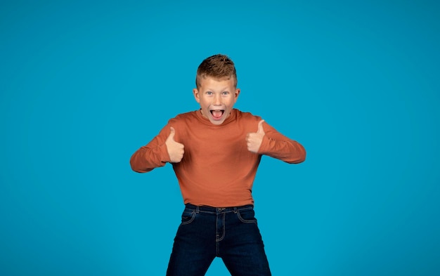 Funny preteen boy showing thumbs up at camera with two hands