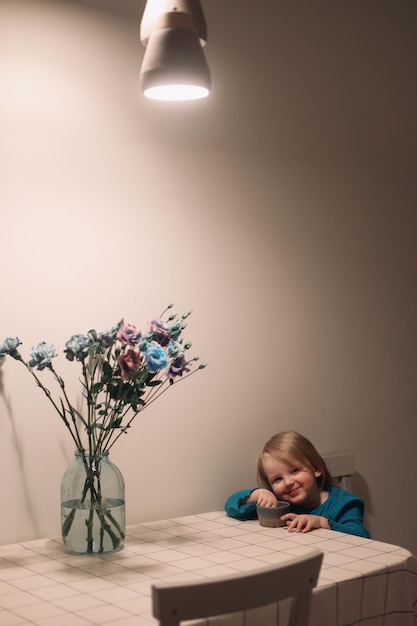 funny smiling little girl eating and sitting at the table family lifestyle