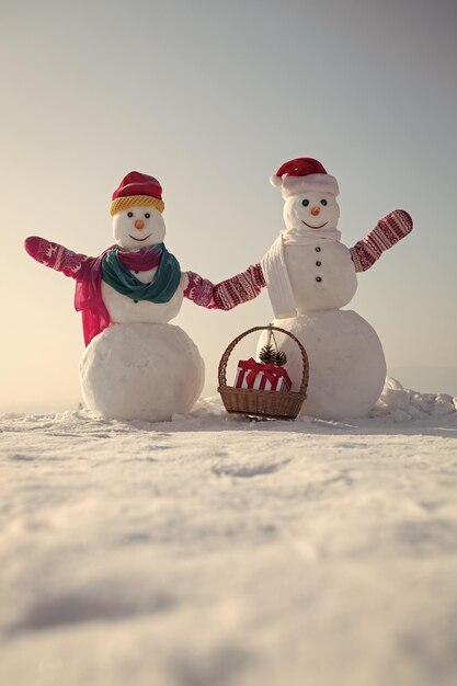 Funny snowmens christmas snowman couple with present box in basket on snow outdoor winter holiday an...