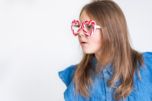 Funny surprised little girl child in caramel glasses look away in surprise. Copy space for text