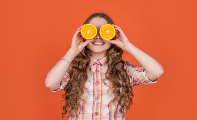 Funny teen girl hold citric fruit on orange background