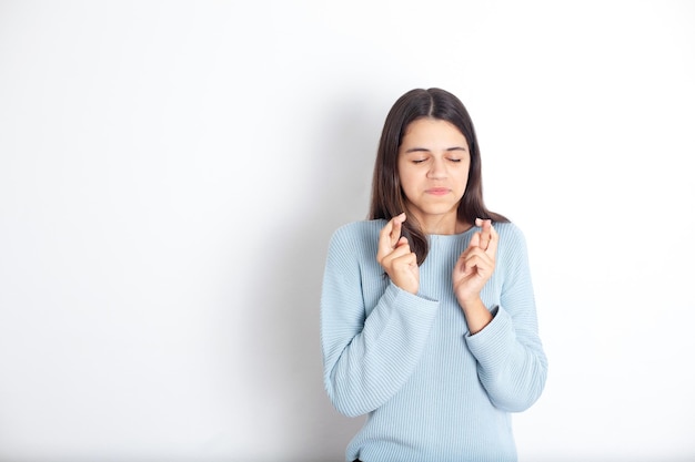 Funny teenage girl made a wish and crossed her fingers for good luck White background space for text