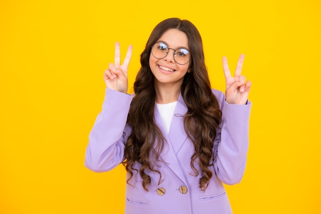 Funny teenager child girl show peace cool vsign isolated over yellow background