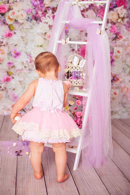 Funny toddler posing in tutu skirt on flower decoration in studio