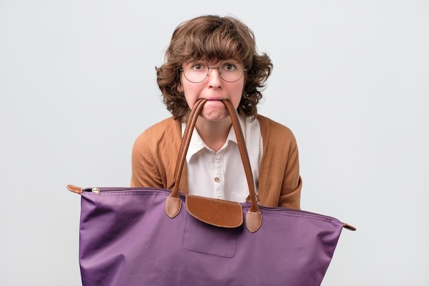 Funny woman in glasses holding shopping bags with her teeth