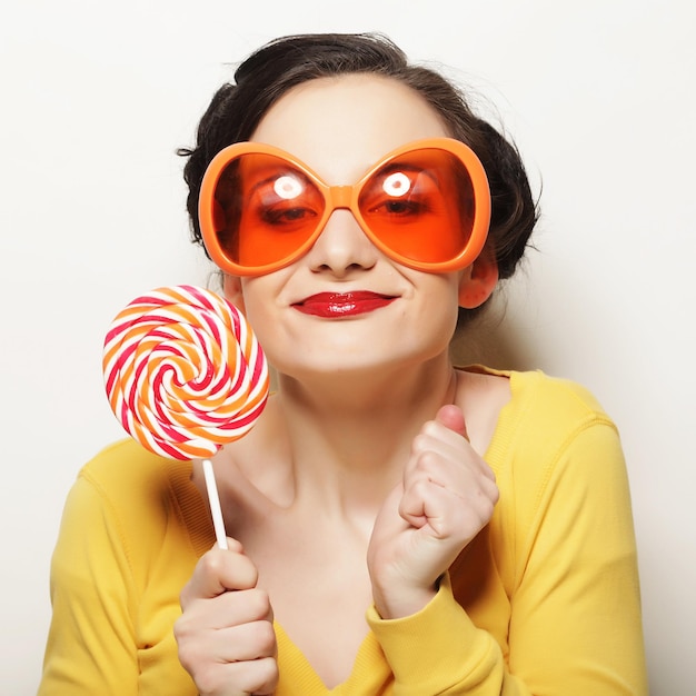 Funny woman wearing big orange glasses holding big lollipop Bir