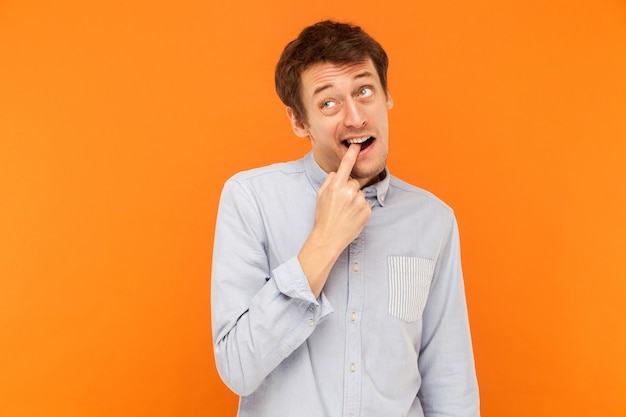 Funny young adult business man touching finger teeth and looking up