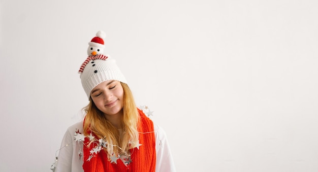 Funny young girl in a Christmas hat with a snowman and a red scarf New Year and Christmas concept