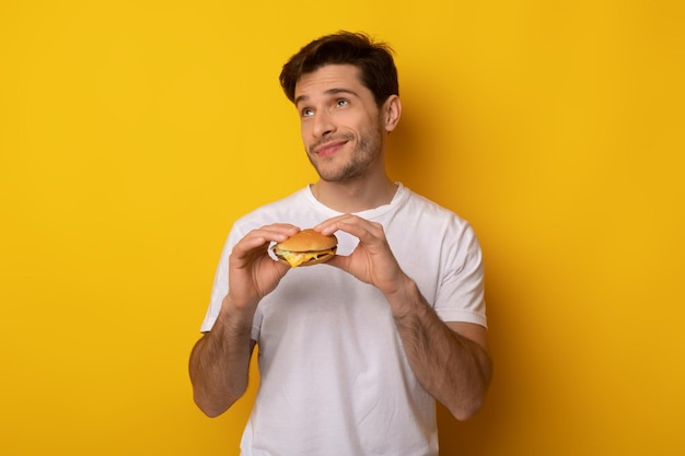 Funny young guy holding burger at studio