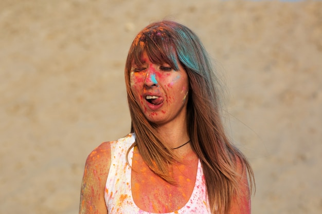 Photo funny young model covered with orange dry paint holi at the desert