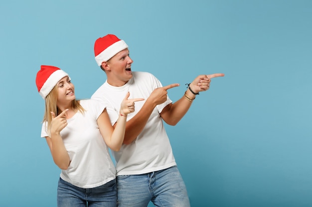 Funny young Santa couple friends guy and woman in Christmas hat posing 