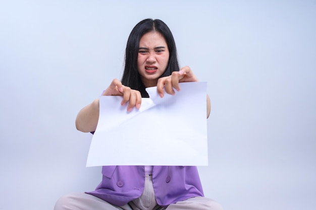 Furious Asian businesswoman tearing a sheet of paper breaking contract