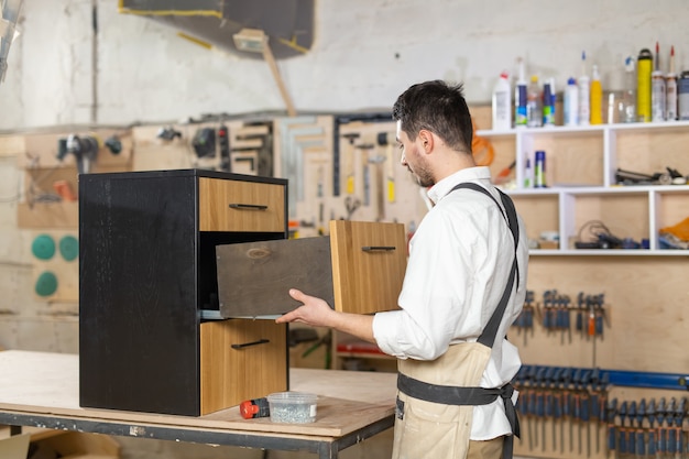 Furniture factory, Small-Sized Companies and people concept - young man working at the furniture production