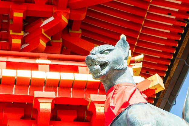 Fushimi inari stone fox guarda wooden gates. Foxes are believed to be messengers of god.