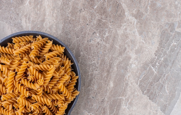 Fusilli pasta in a pan, on the marble.