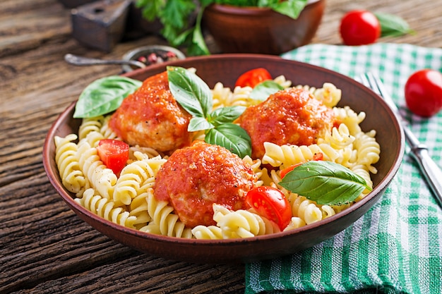 Fusilli  pasta with meatballs in tomato sauce and basil in bowl