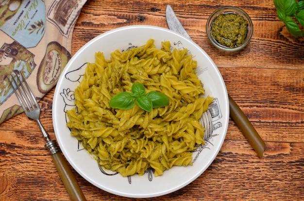 Fusilli pasta with pesto sauce in a plate on a wooden table