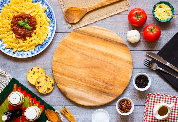 Fusilli pasta with tomato sauce, tomatoes, onion, garlic, dried paprika, olives, pepper and olive oil on wood