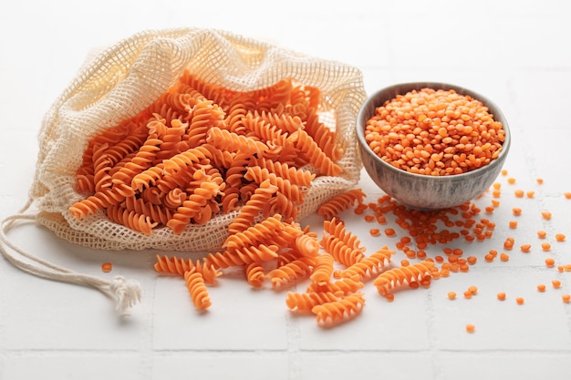 Fusilli red lentil pasta on a white tile background