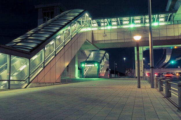 Futuristic structure of modern pedestrian pathway over empty city square by night