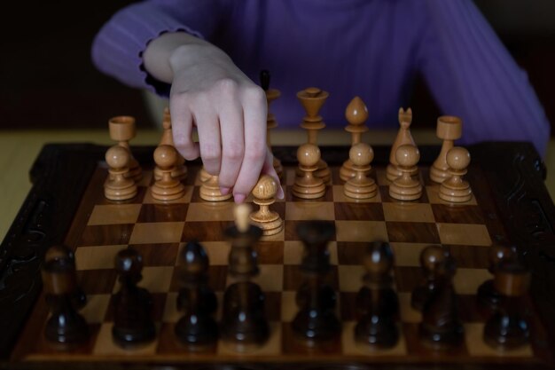 A game of chess The girl is holding a pawn in her hands Dark dramatic photo style in dark colors