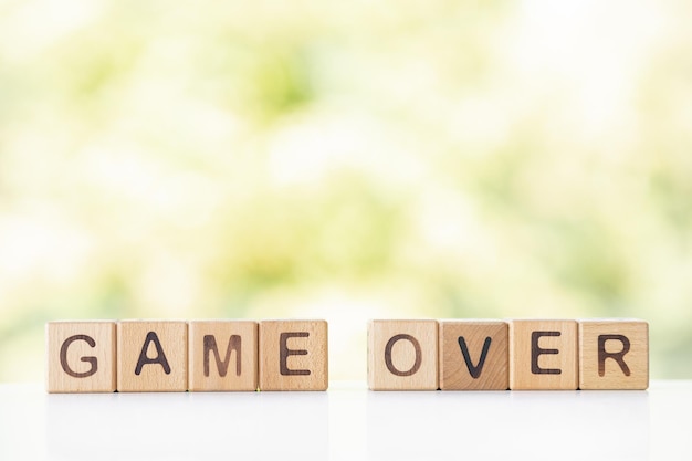 Game over is written on wooden cubes on a green summer background Closeup of wooden elements