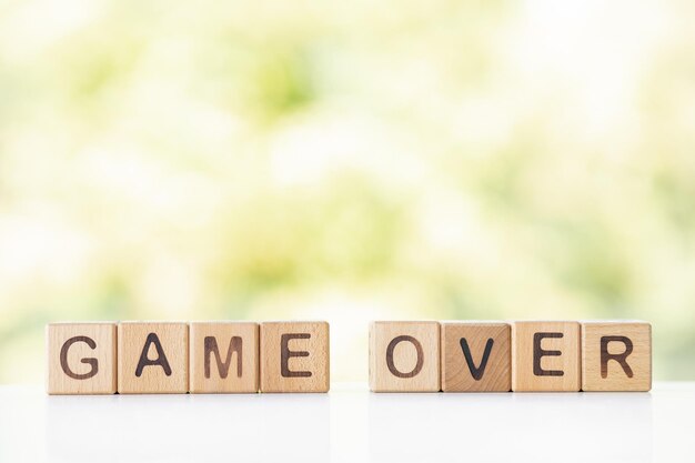 Game over is written on wooden cubes on a green summer background Closeup of wooden elements