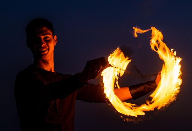 Photo game of light and dark fire spinner at night happy male spinner spin burning poi