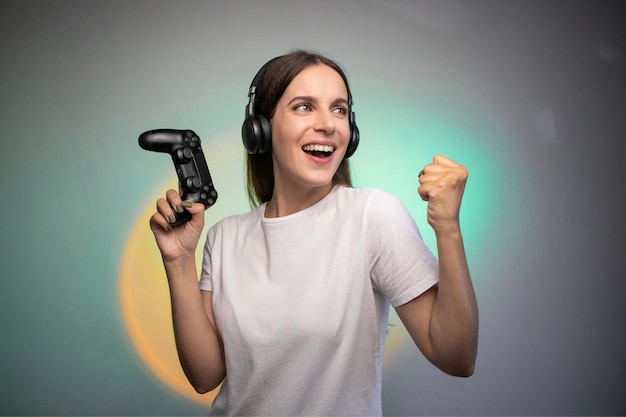 Game win. Happy female gamer in headphones rejoices in the victory in the game. Emotional gamer.