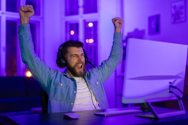 Gamer with arms raised in triumph at night