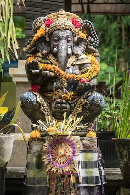 Ganesh Statue decorated with floweers in a temple in Ubud Bali Indonesia