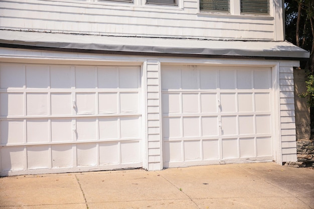 A garage door with white panels and a black car parked in front of it.