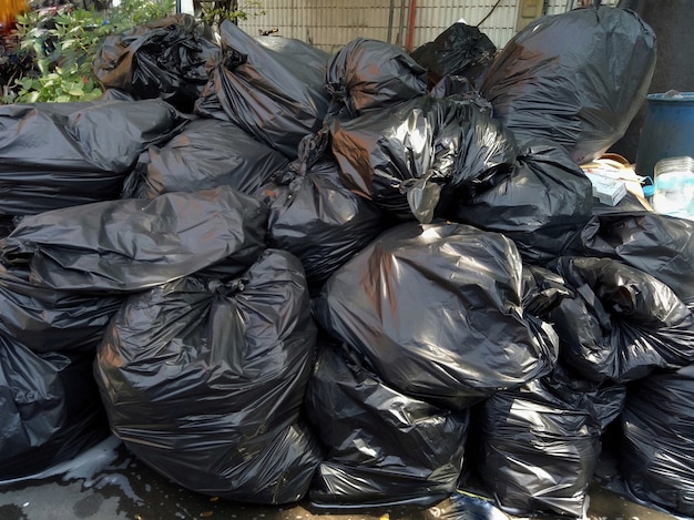 Garbage bags, black bin bags, on the floor in the park. Environment and object concept.