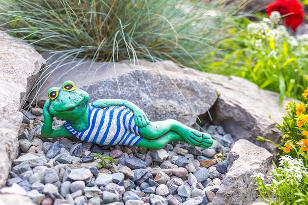 A garden sculpture of a frog lying on the floor reading a book