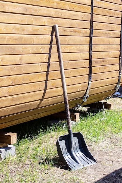 A garden shovel stands by a wooden shed