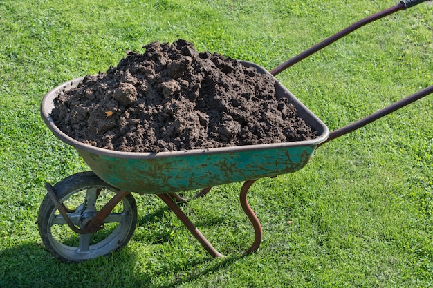 Photo garden-wheelbarrow filled with soil on a farm.