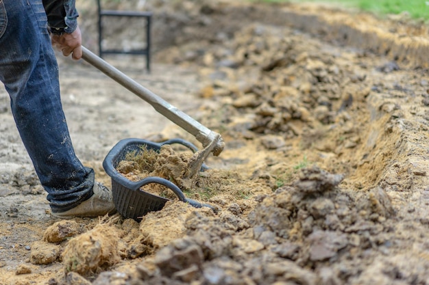 Photo gardener digs the soil with his equipment for gardening and prepare land for plantation.