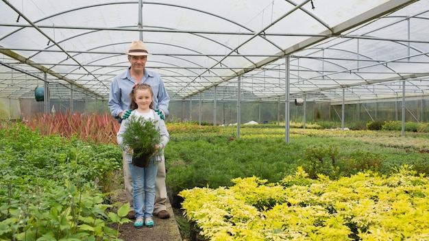 Gardener and granddaughter holding a large potted plant