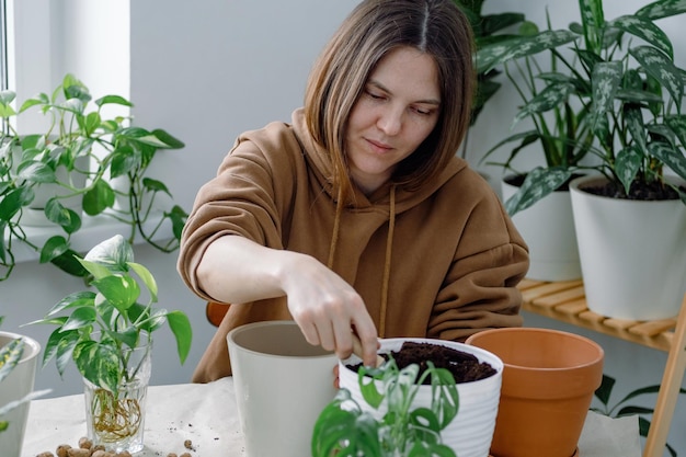 A gardener holding a shovel and filling a flowerpot with soil preparing it for potting Urban jungle