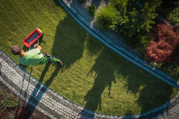 Photo gardener using a fertilizing distributor to feed the grass