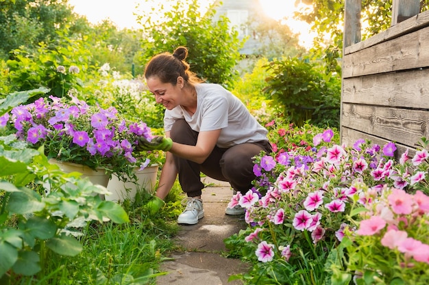 Gardening and agriculture concept Young woman farm worker gardening flowers in garden Gardener planting flowers for bouquet Summer gardening work Girl gardening at home in backyard