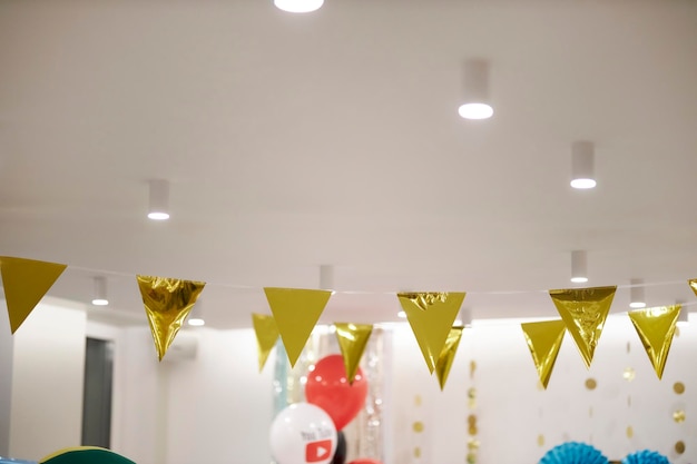 garland of golden triangles on a rope. Gold paper garlands on a white wall. foil flags on a string.